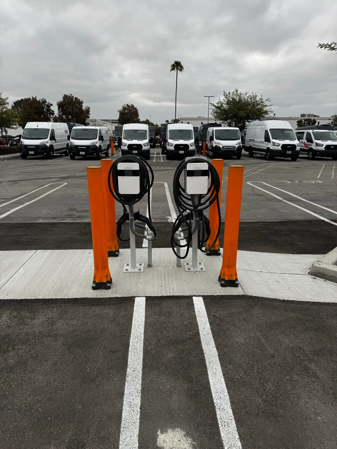 Two pedestal EV chargers with cable management at a fleet lot